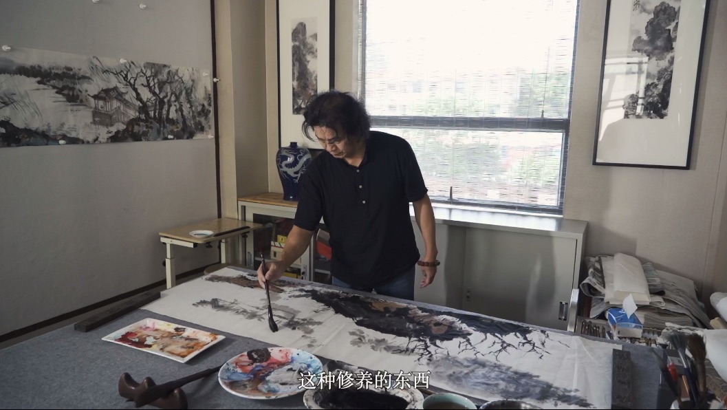 Zhou Bo painting at his studio table