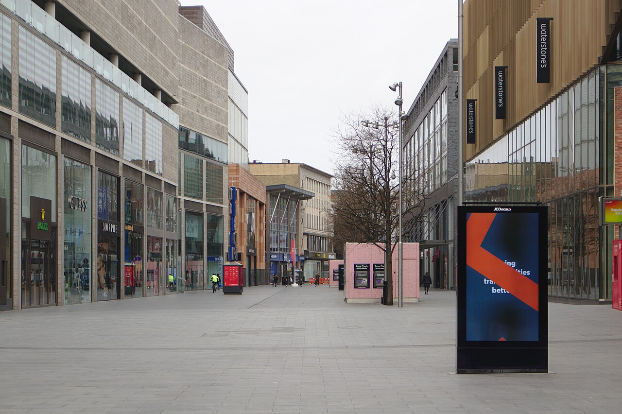 An empty pedestrianised shopping street with retail signage and no people, photographed during the 2020 lockdown.