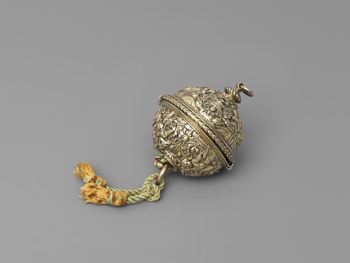 A very small gilded silver rosary bead on a green cord, seen from far across a dark gallery.