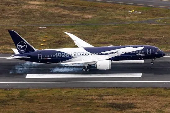 Lufthansa Boeing 787-9 in the 1926–2026 centenary livery, deep navy fuselage with the anniversary years running its length, landing with reverse thrust visible.
