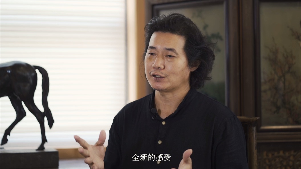 Portrait of Zhou Bo speaking in his studio