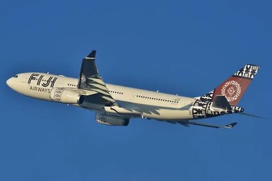Fiji Airways Airbus A330 climbing after takeoff, masi tapa motifs on the tail against a deep blue sky.