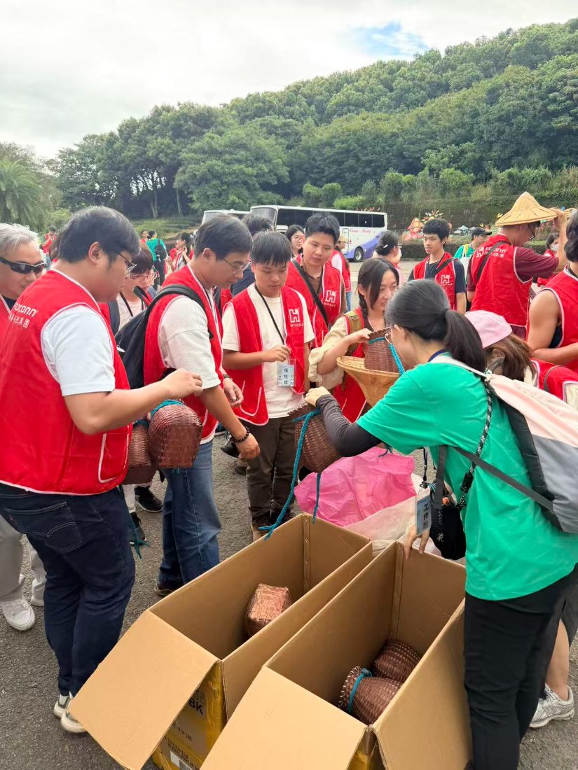 Staff handing out woven bamboo picking baskets from cardboard boxes at the bus park