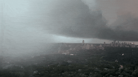 Dark cloud pressed low over the city with rain sweeping across the foreground