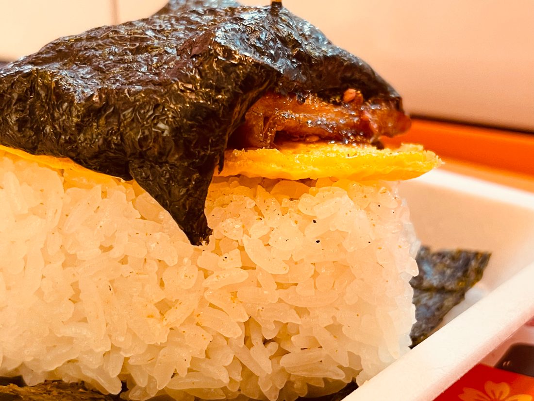 Close-up of the handmade onigiri — nori, egg, and glistening rice