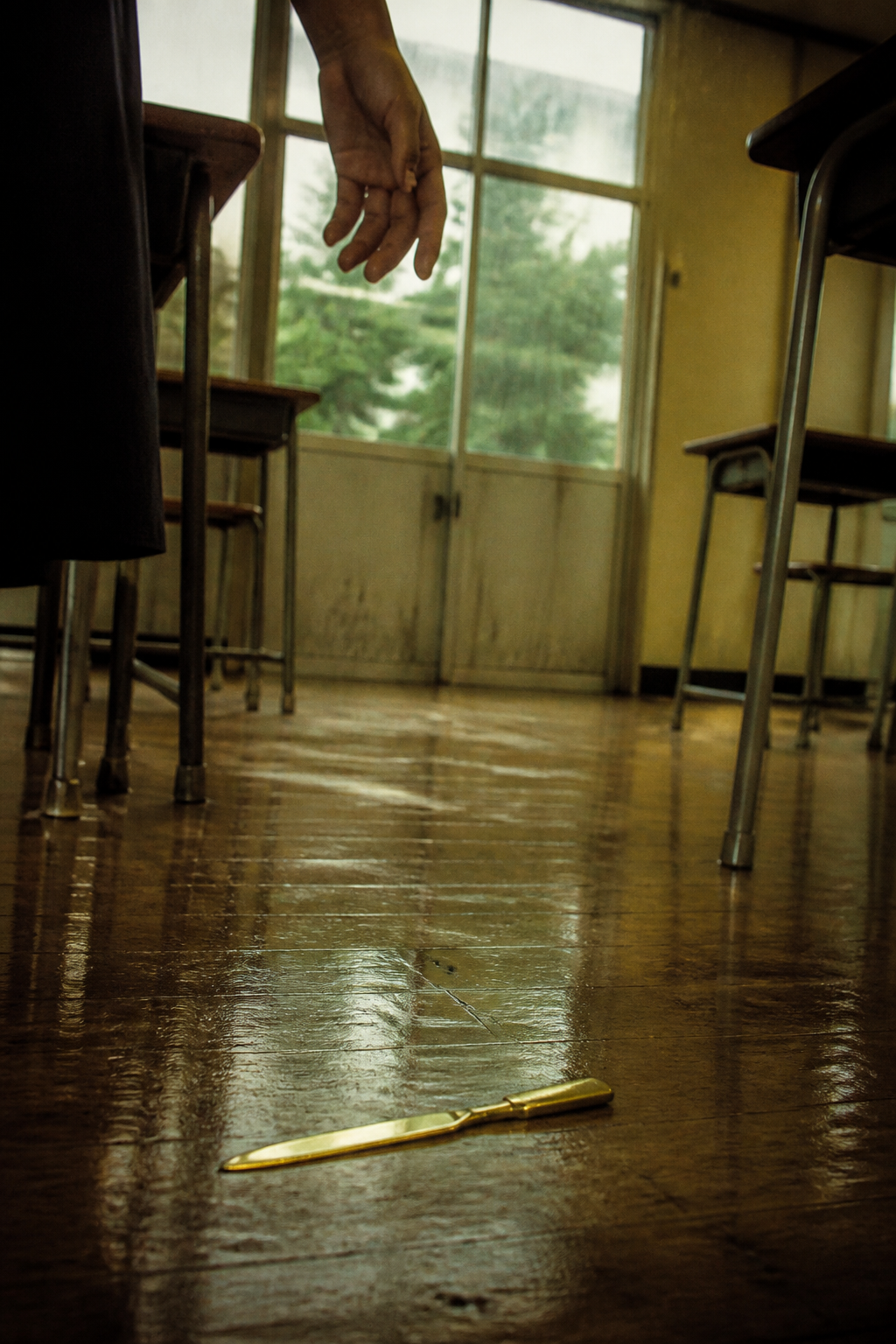 旧木地板上黄铜裁纸刀、垂落的手与雨水反光