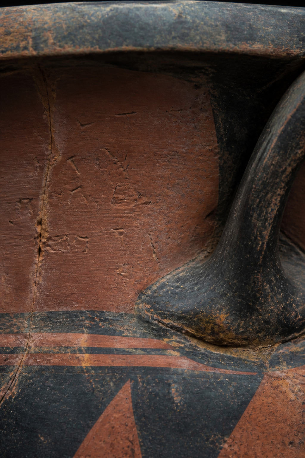 A red-figure Greek krater lit against a dark ground, the painted figures legible across its belly.